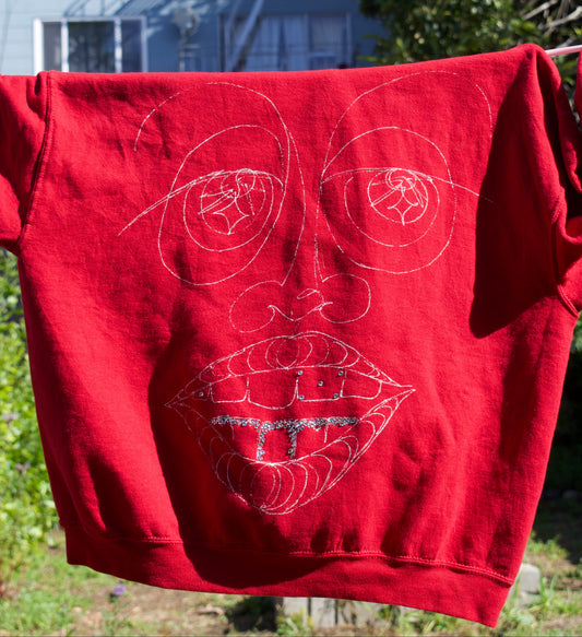 Red sweatshirt with white designs hanging outdoors