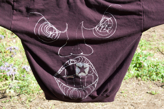 Brown garment with white embroidered designs on a natural background